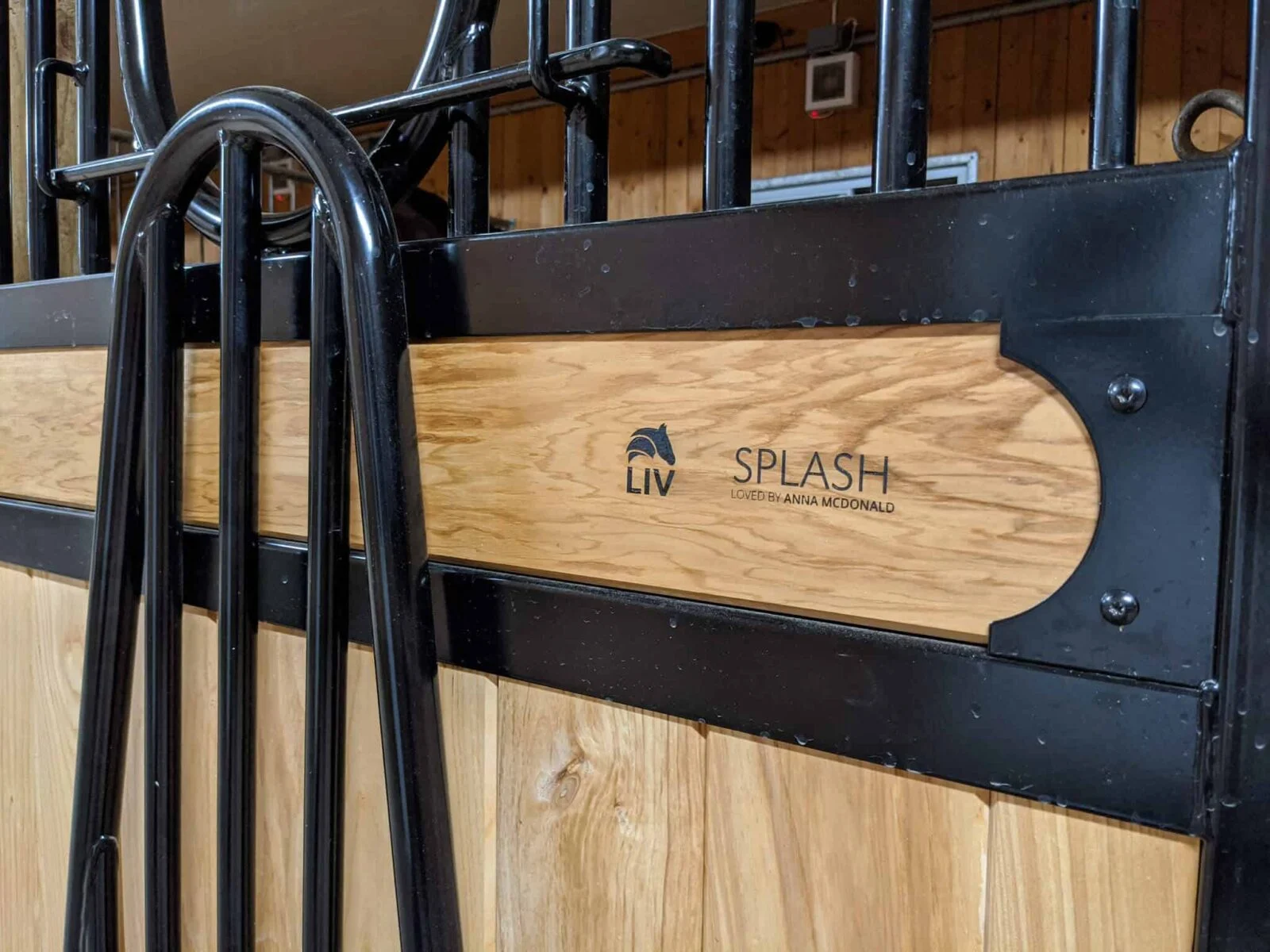 a horse stall with a wooden door and a black and white logo