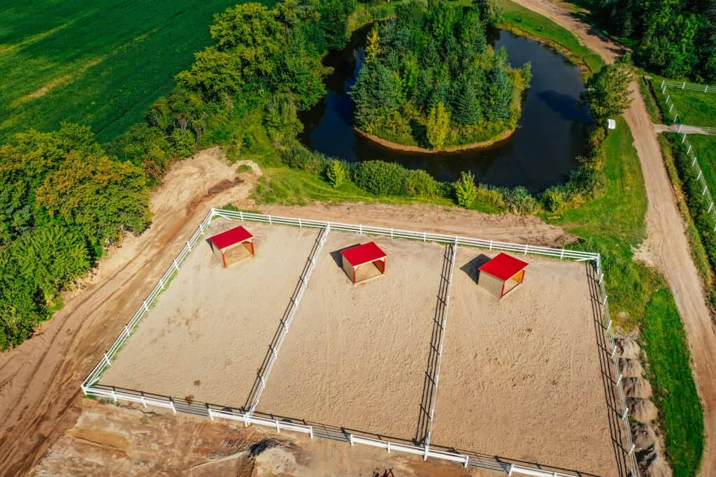 an aerial view of a horse barn with two red roofs