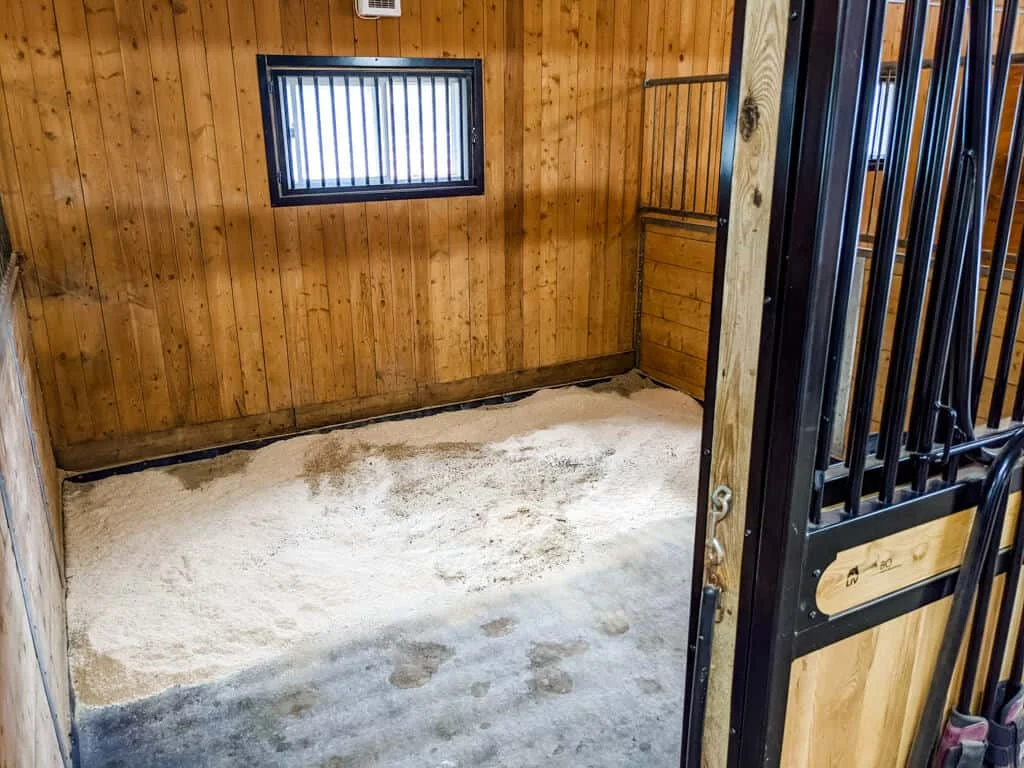a horse stall with a wooden stall door and a wooden floor