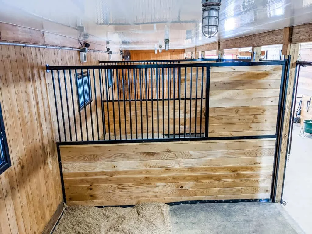 a horse stall with a wooden wall and a wooden floor