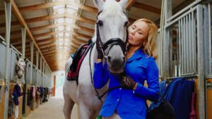 Middle-Aged Woman With Her Horse In A Stall